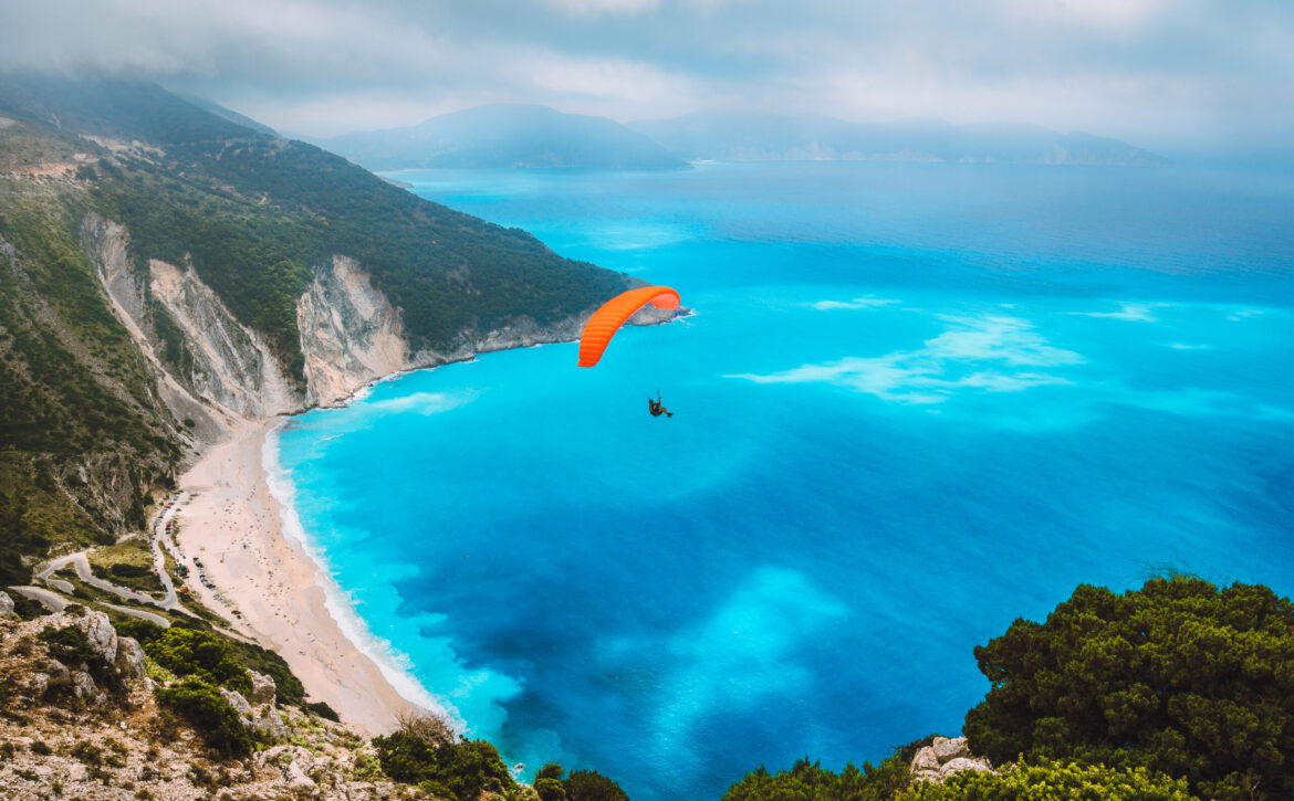 Aerial view of the paraglider flying over gorgeous Myrtos beach. Amazing water colors and beautiful coastline on kefalonia island, Greece